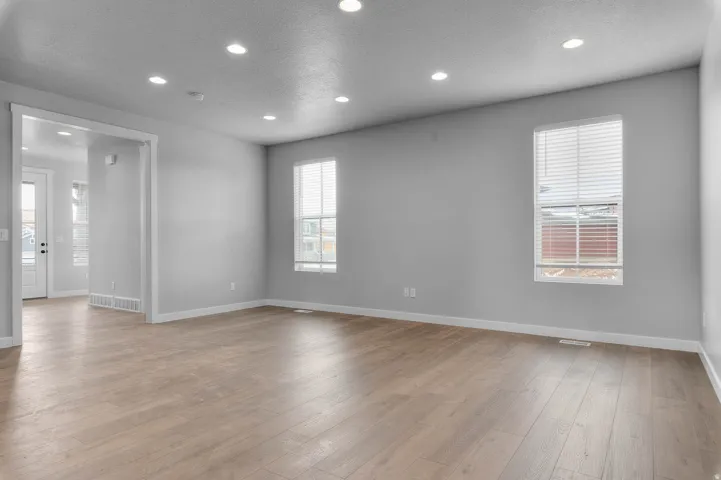 Spacious room featuring wood-finish flooring, recessed lighting, and two windows with blinds