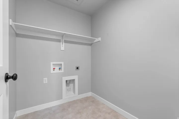 Dedicated utility space featuring a built-in shelf, washer and dryer hookups, and light-toned flooring