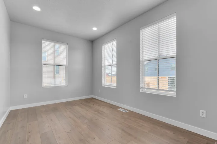 Recessed ceiling lighting, wood-finish flooring, multiple windows with blinds, and light gray wall paint