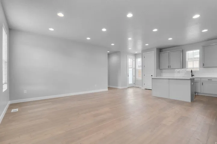 Spacious open-concept area featuring light wood-finish flooring, recessed lighting, and a kitchen island with a white countertop