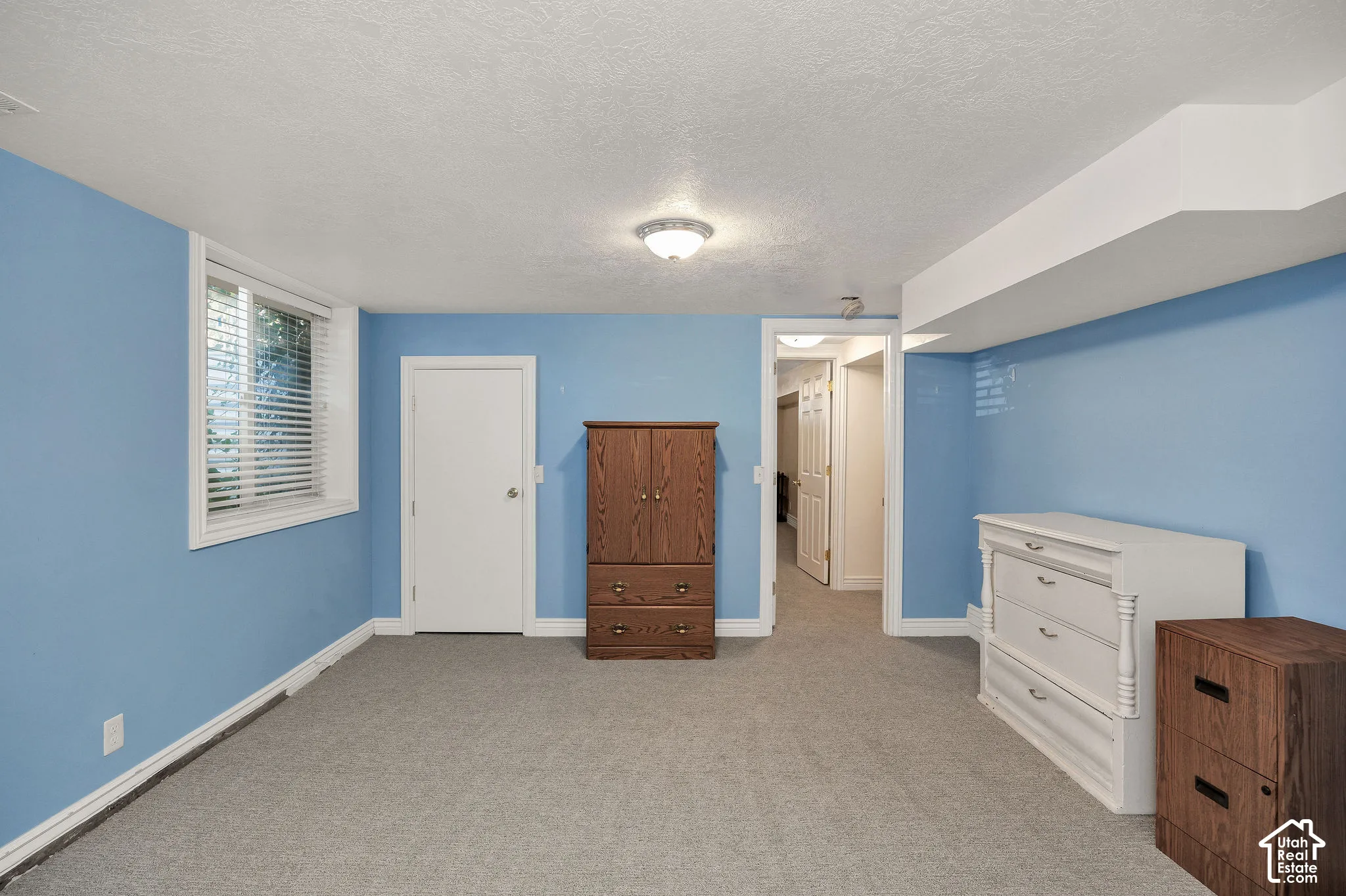 Recessed window with blinds, carpeted flooring, overhead lighting, white trim, and a white interior door