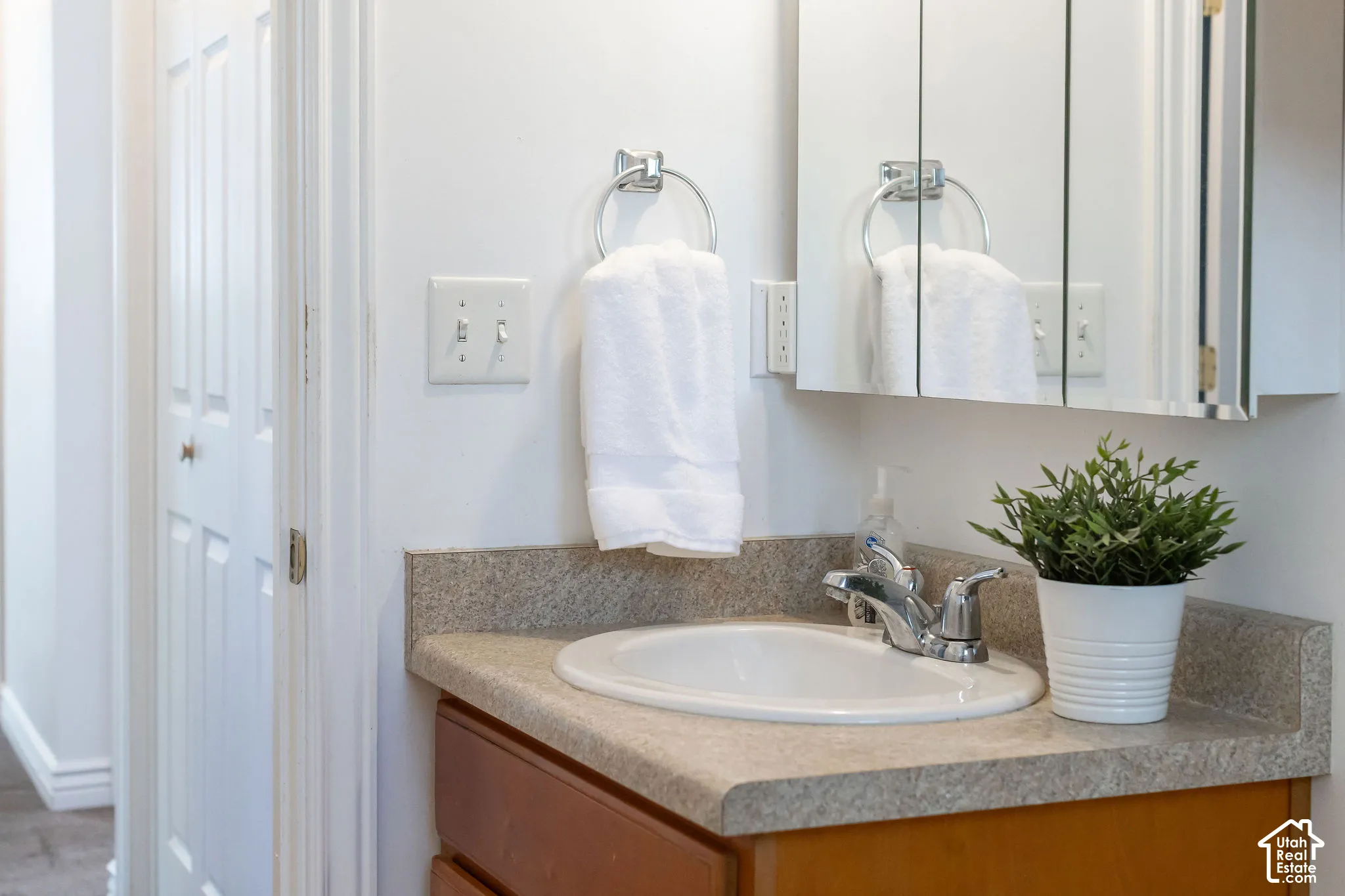 Vanity with integrated sink, chrome faucet, and mirrored medicine cabinet