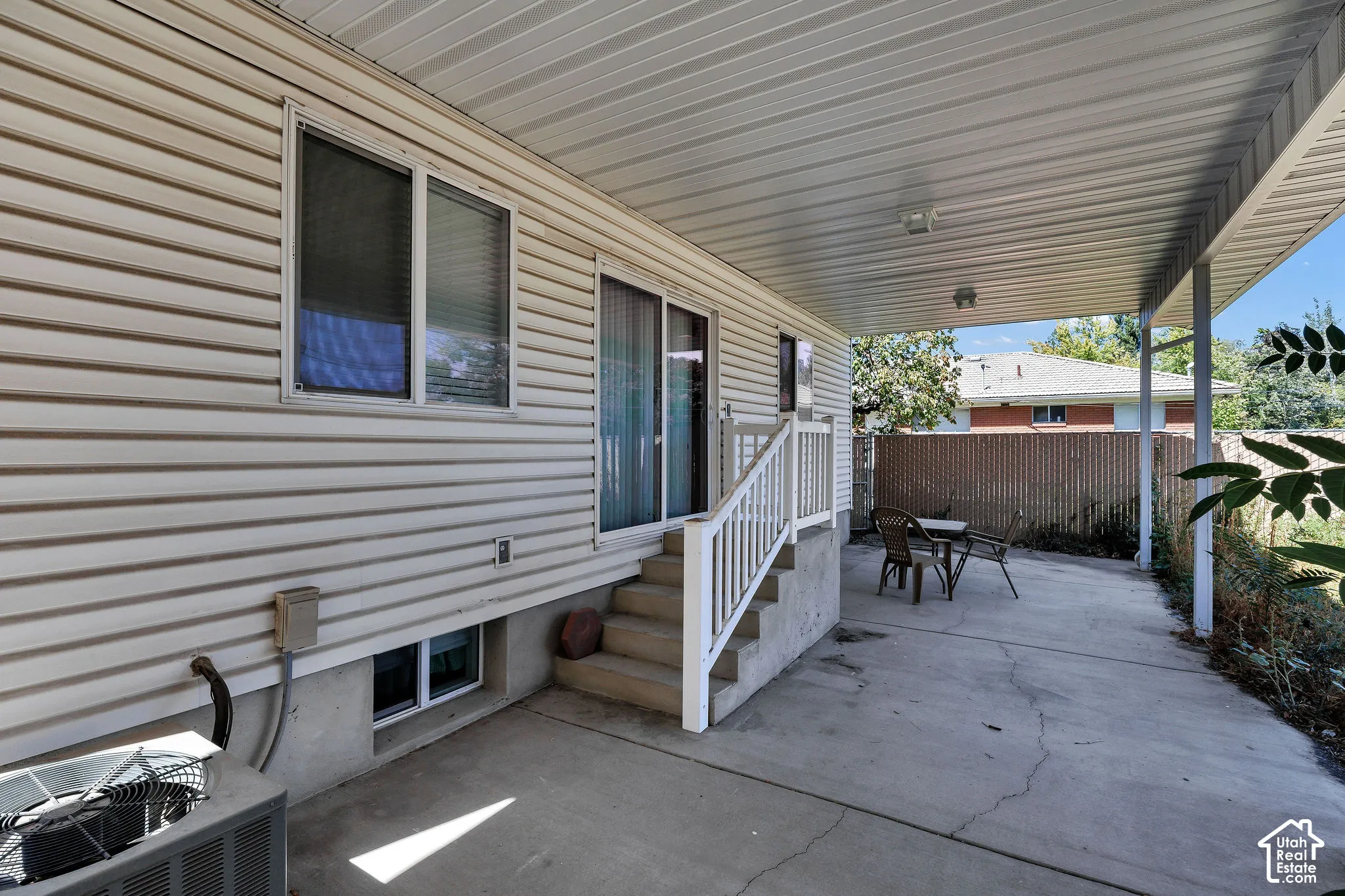 Covered concrete patio with white vinyl siding exterior and sliding glass door access