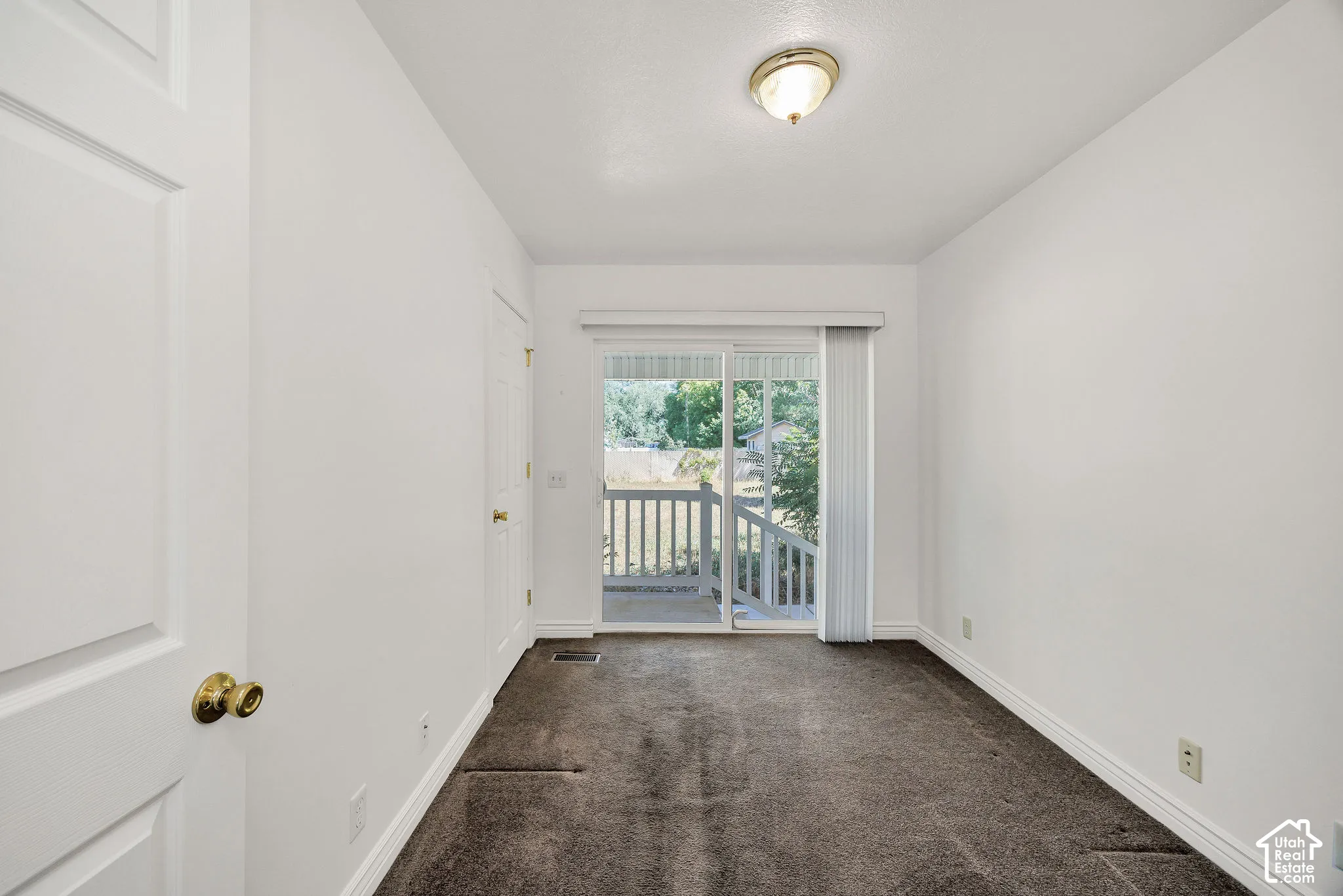 Sliding glass door leading to an outdoor deck with white railings