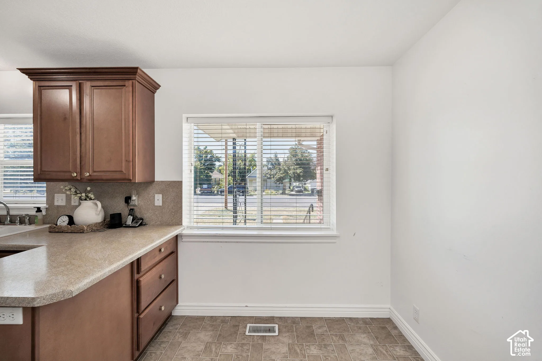 Warm wood-finish cabinetry, neutral countertops, and a tiled backsplash