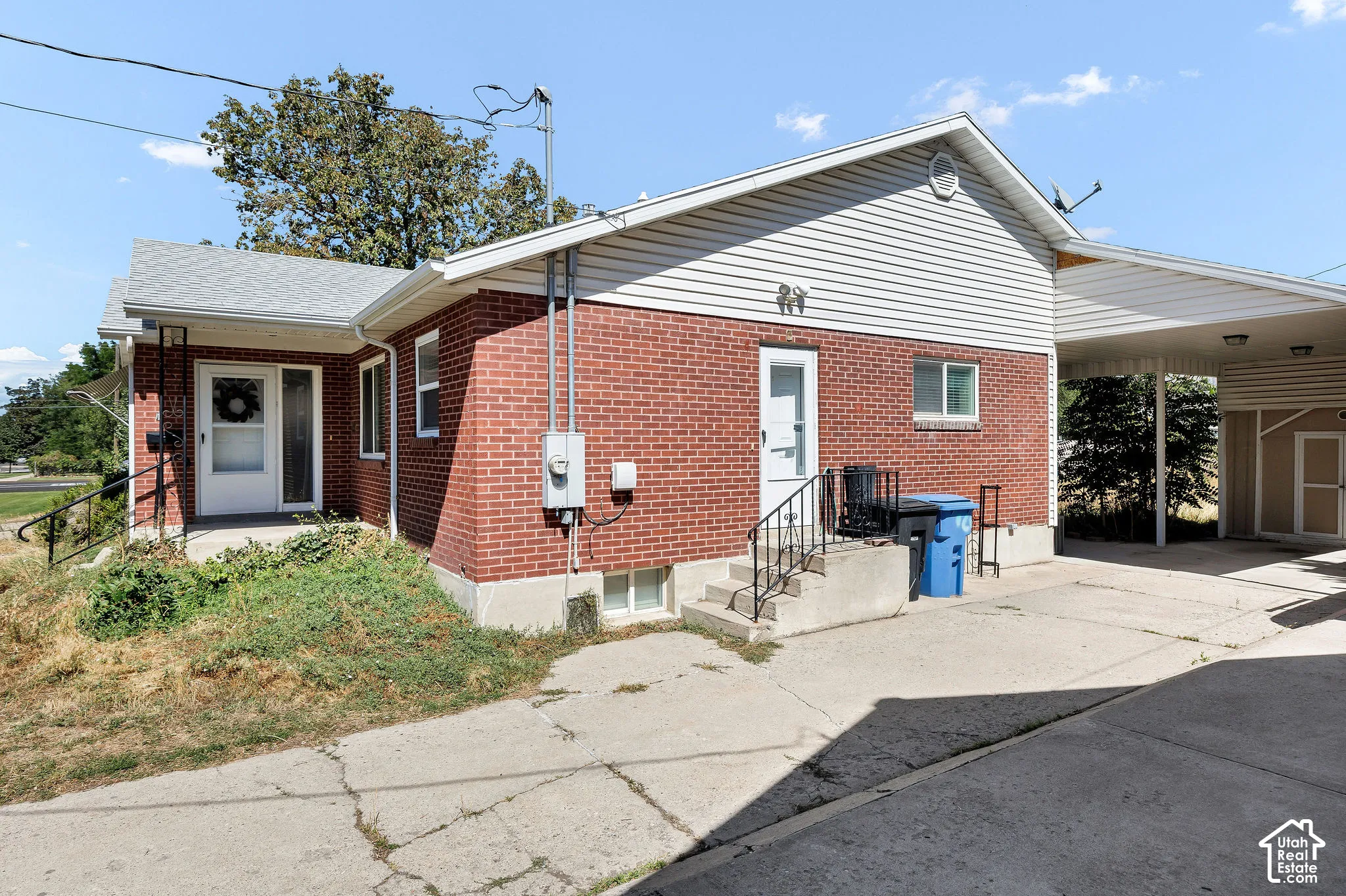 Brick exterior with white siding accents and a covered carport