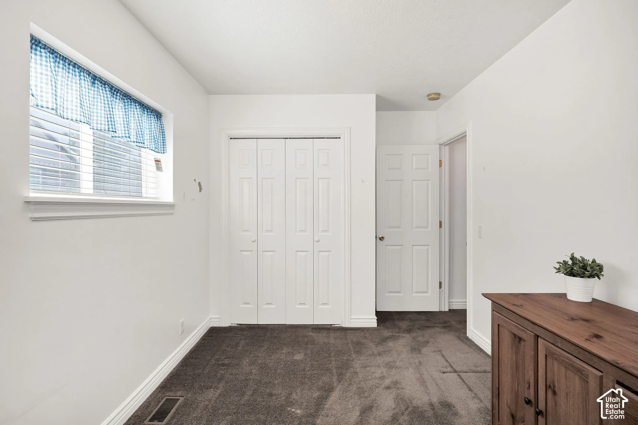 White walls, dark gray carpeting, and bi-fold closet doors