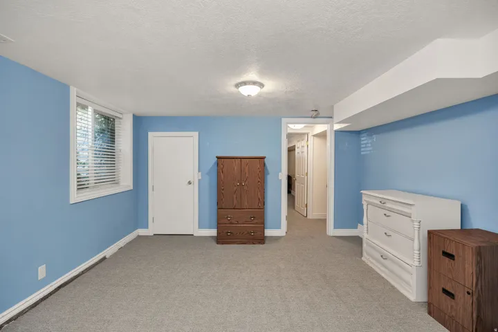 Recessed window with blinds, carpeted flooring, overhead lighting, white trim, and a white interior door