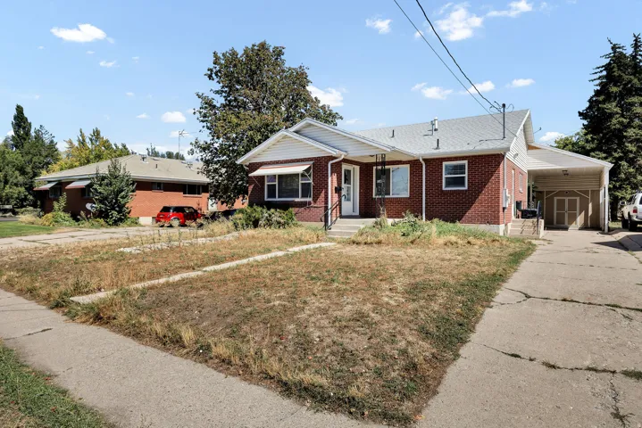 Brick exterior with white trim, covered entryway, and a carport with an enclosed storage area
