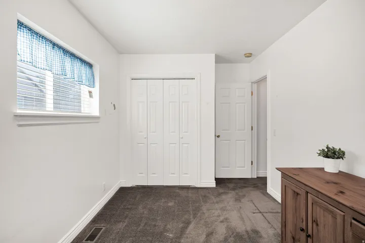 White walls, dark gray carpeting, and bi-fold closet doors