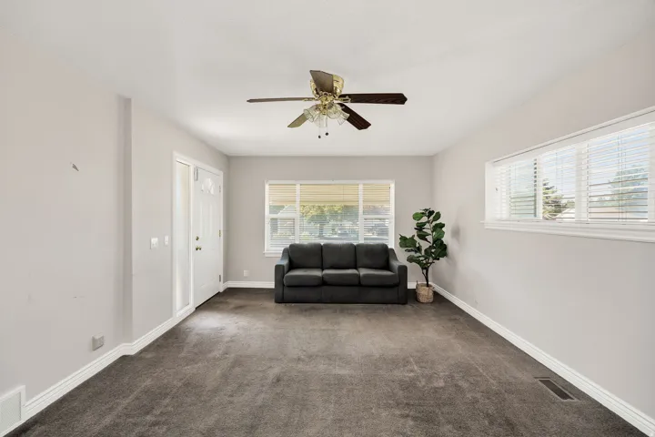 Recessed lighting, ceiling fan, carpet flooring, multiple windows, and a white entry door