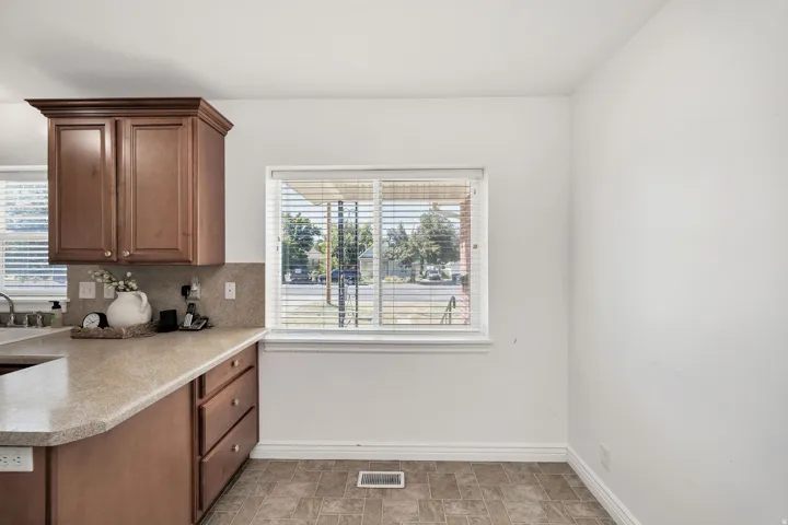 Warm wood-finish cabinetry, neutral countertops, and a tiled backsplash