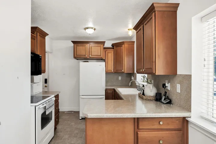 Kitchen featuring wood cabinetry, stone-finish countertops, tile backsplash, and a double basin sink