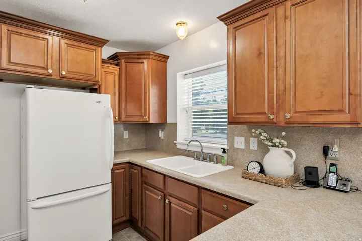 Wood-finish cabinetry with crown molding, laminate countertops, and a double basin sink with a chrome faucet