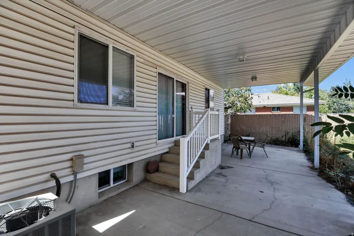 Covered concrete patio with white vinyl siding exterior and sliding glass door access