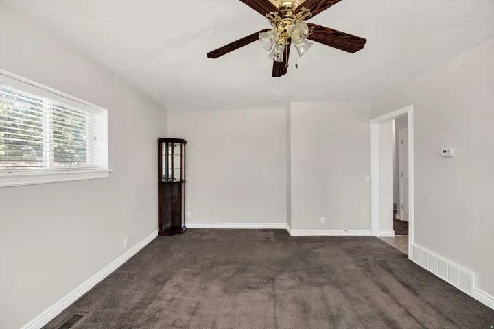 Recessed window with horizontal blinds, overhead ceiling fan with lighting, and doorway with white trim