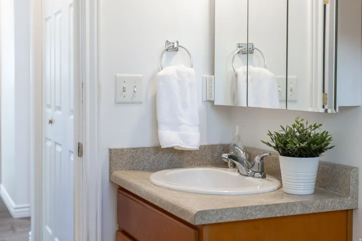 Vanity with integrated sink, chrome faucet, and mirrored medicine cabinet
