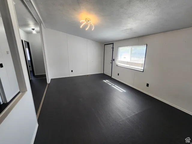 Spacious living area with dark flooring, white panel walls, and an overhead lighting fixture