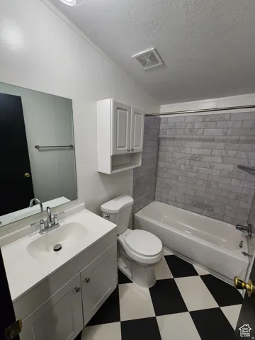 Bathroom featuring a white vanity with integrated sink, chrome faucet, wall-mounted mirror, white wall cabinetry, and a white bathtub with subway tile surround