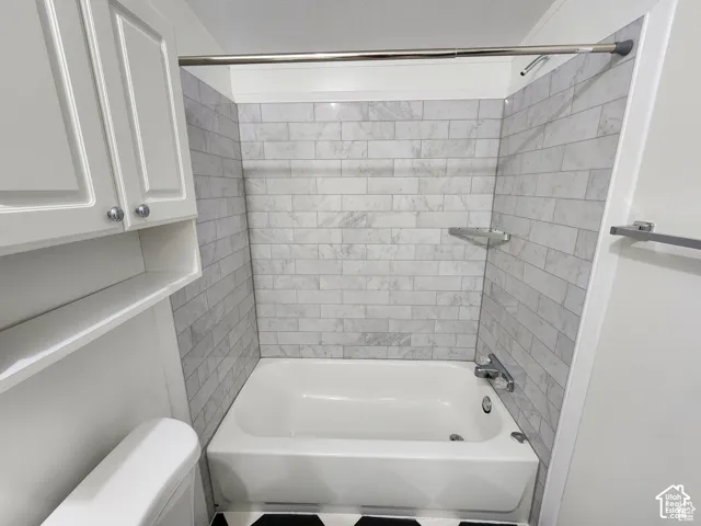 White bathtub with subway-style tiled surround, chrome fixtures, and corner shelving