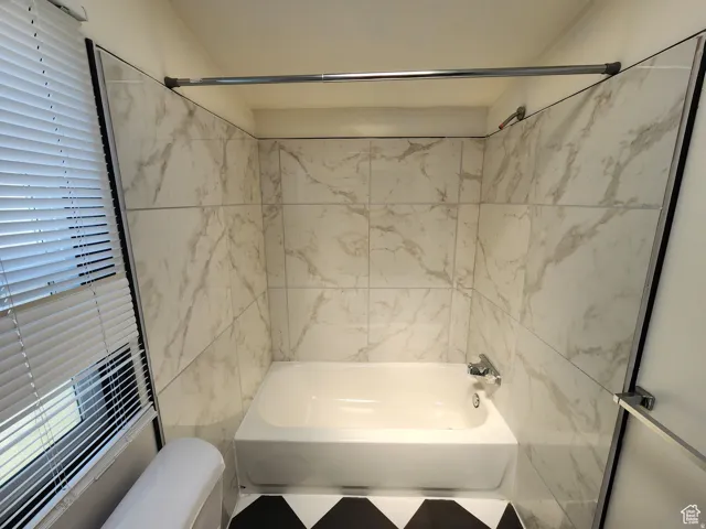 Bathtub with wall-mounted fixtures, white tile surround, and chrome shower rod