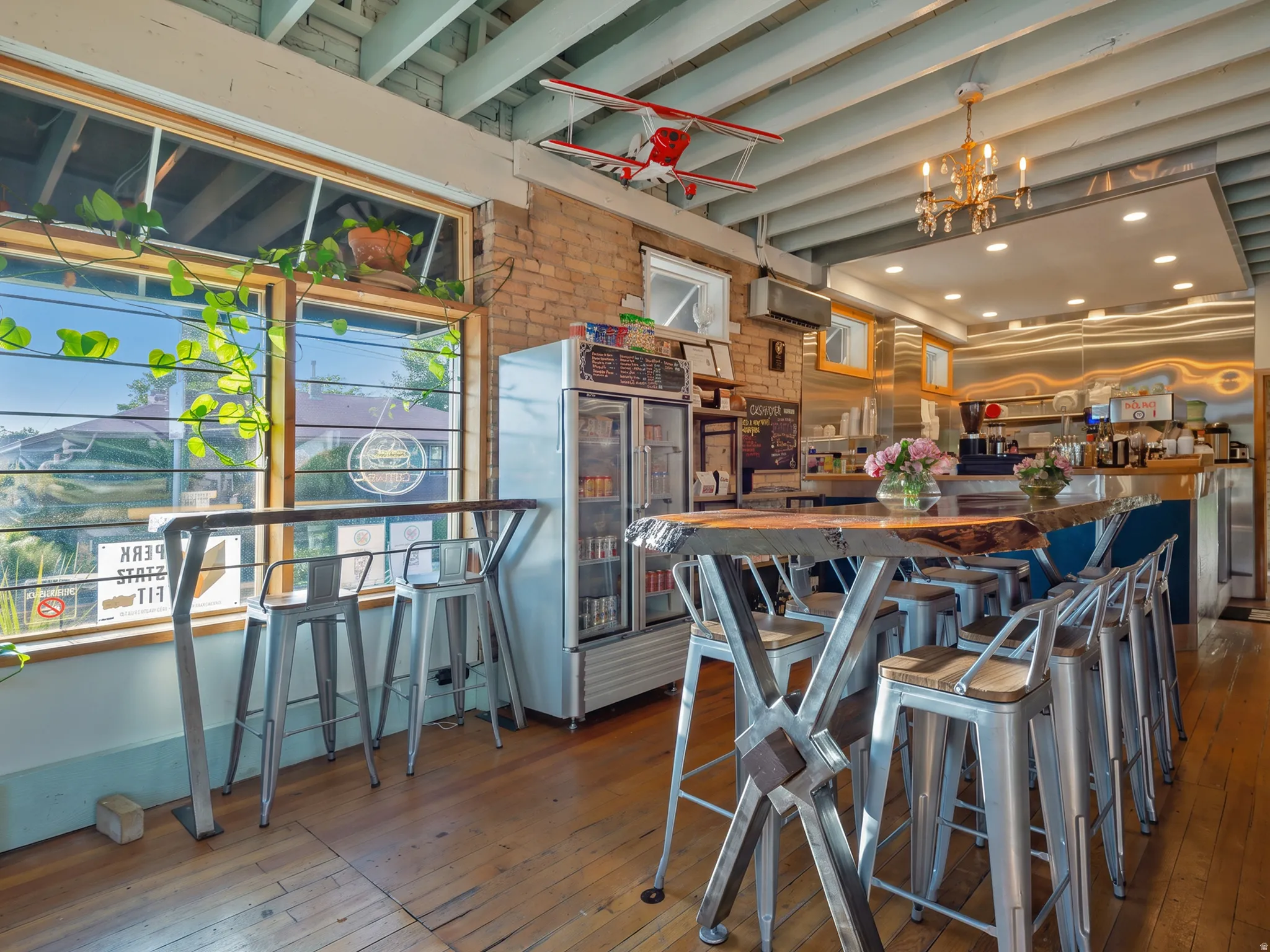 Exposed brick walls, wood-finish flooring, high ceilings with exposed beams, large storefront window
