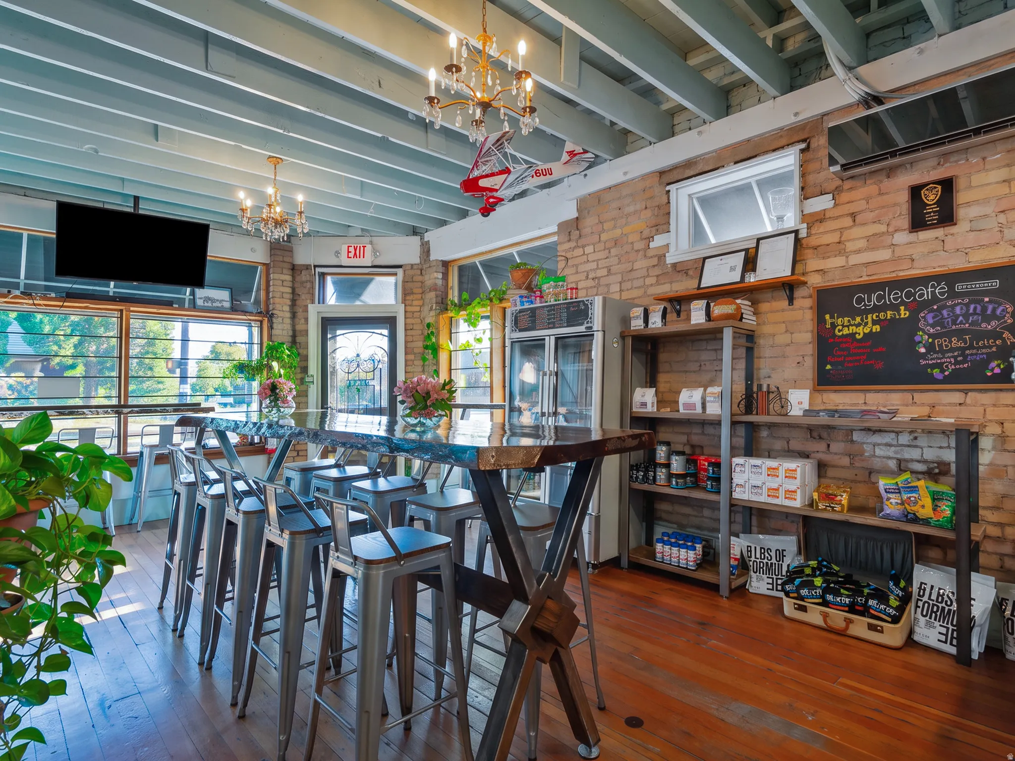 Exposed brick walls, wood-finish flooring, and an open-beam ceiling, storefront windows