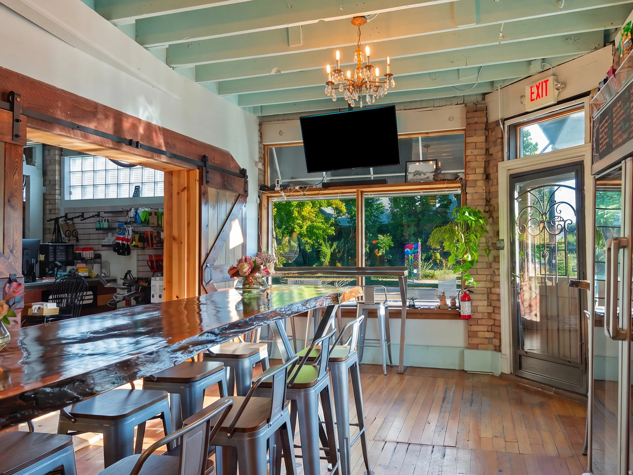 Hardwood flooring, exposed brick wall, large front windows, barn door entryway, and a decorative chandelier