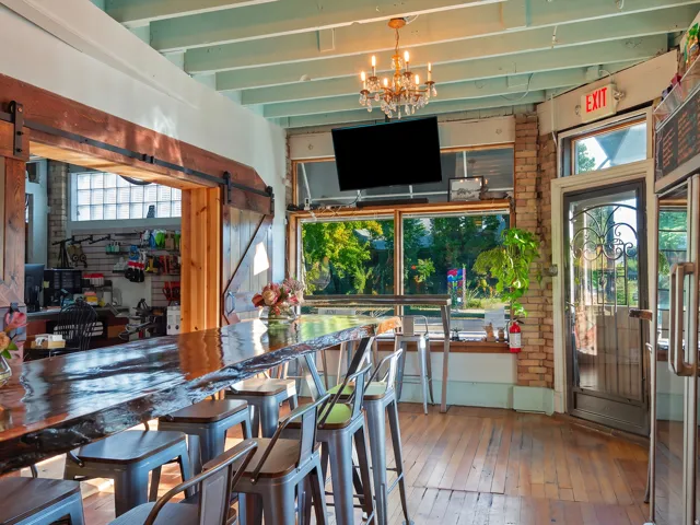 Hardwood flooring, exposed brick wall, large front windows, barn door entryway, and a decorative chandelier