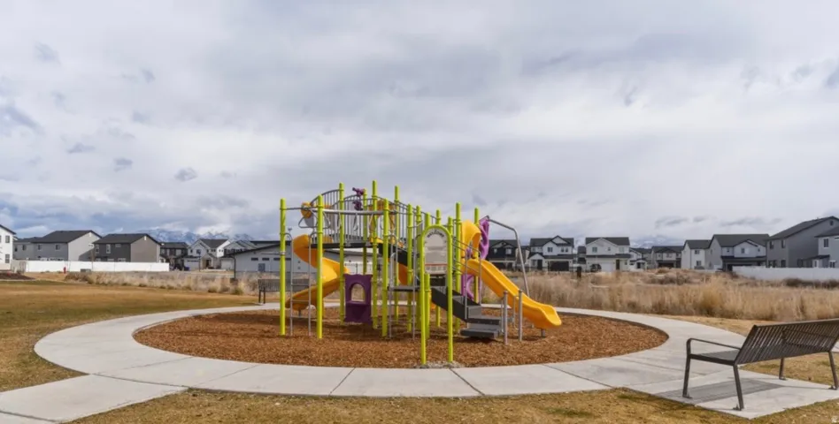 Outdoor play structure with multiple slides and climbing elements, surrounded by a wood chip base