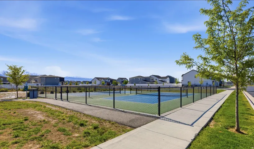 Paved pathways, green space, and dual tennis courts with chain-link fencing
