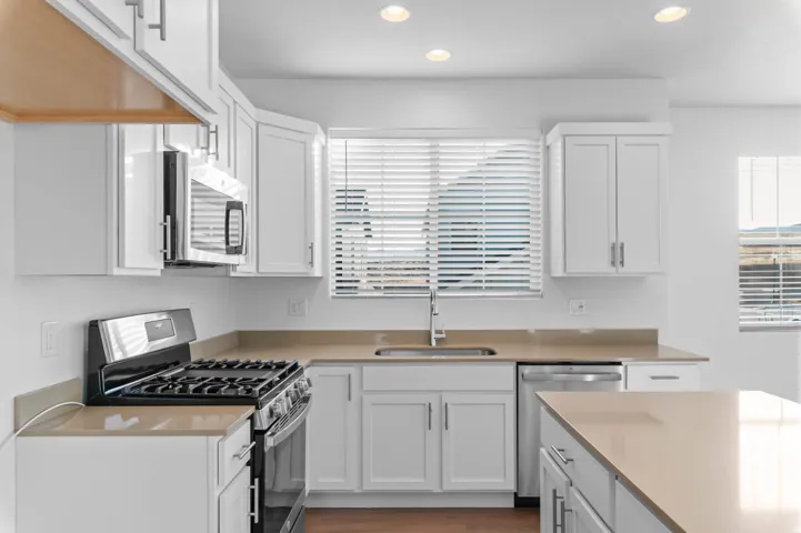 Modern kitchen featuring white cabinetry, stainless steel appliances, light-toned countertops, and recessed lighting
