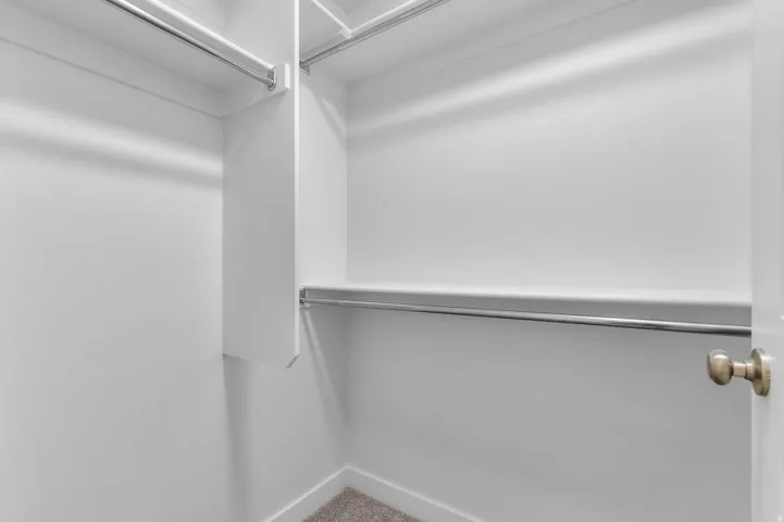Built-in closet shelving system with multiple chrome hanging rods and soft carpet flooring