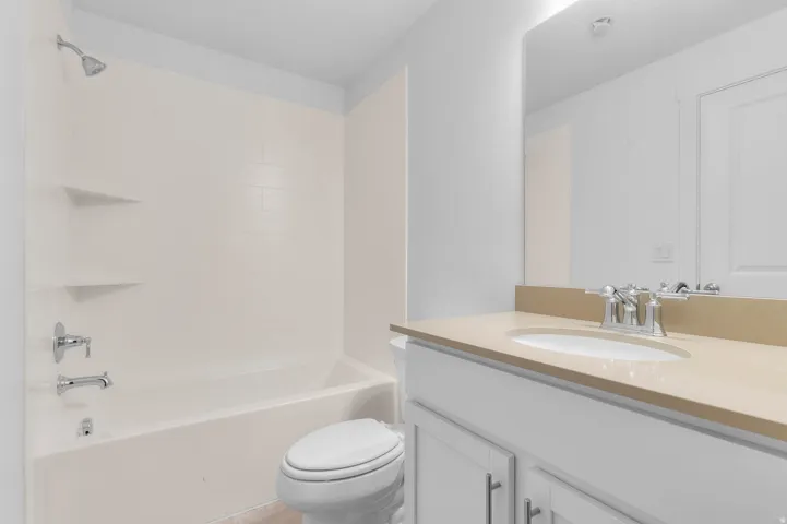 White vanity with cabinet storage, a light-toned countertop, and an undermount sink with a chrome faucet
