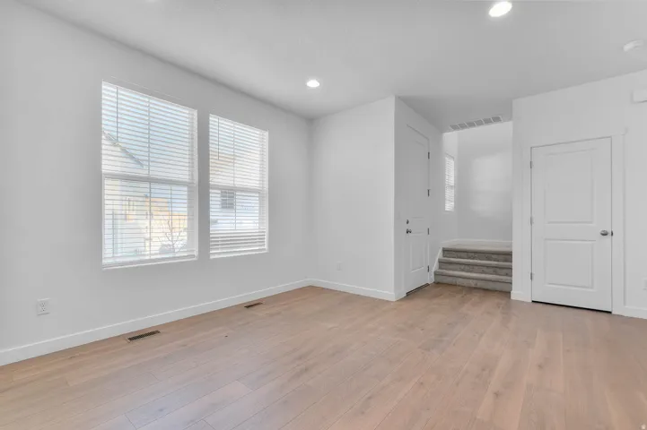 Wood-finish flooring, recessed lighting, and multiple windows with blinds