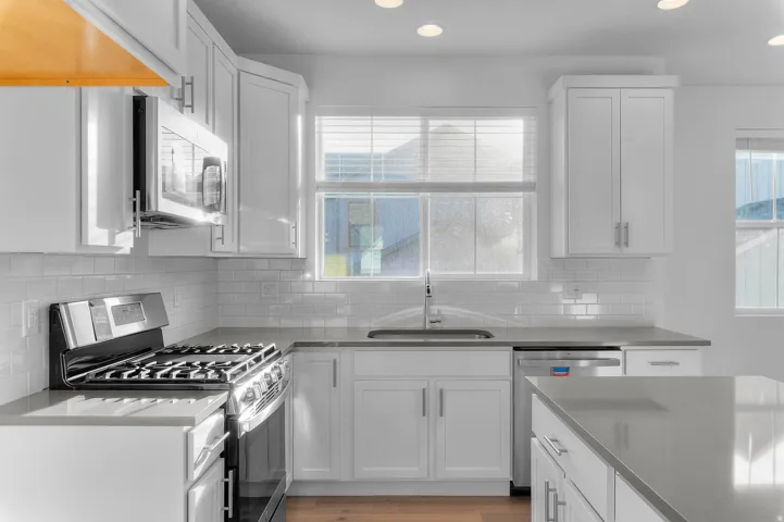 Modern kitchen featuring white shaker cabinetry, stainless steel appliances, light gray countertops, subway tile backsplash, and recessed lighting
