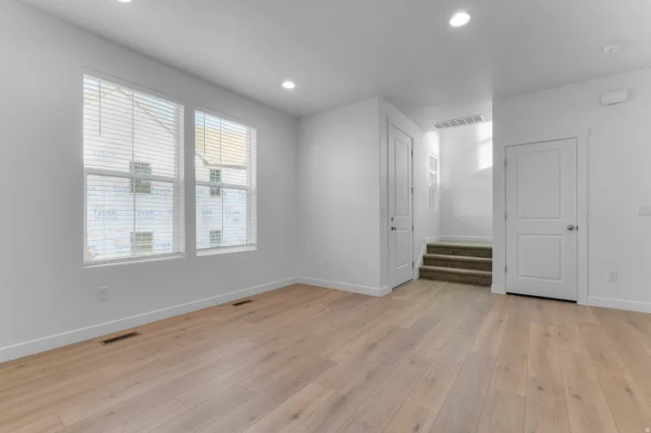 Wood-finish flooring, recessed lighting, and multiple windows with blinds