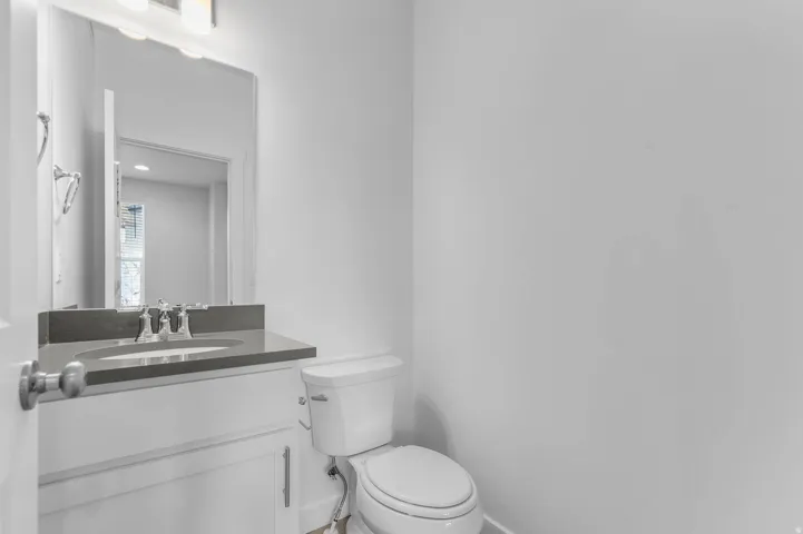 White vanity with a gray countertop and integrated sink, chrome faucet, and rectangular mirror