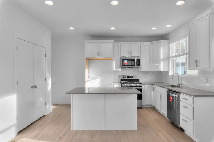 Kitchen with recessed lighting, light wood-finish flooring, white cabinetry, a central island, and stainless steel appliances