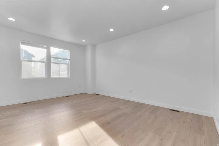 Light wood-finish flooring, recessed lighting, and two windows with blinds