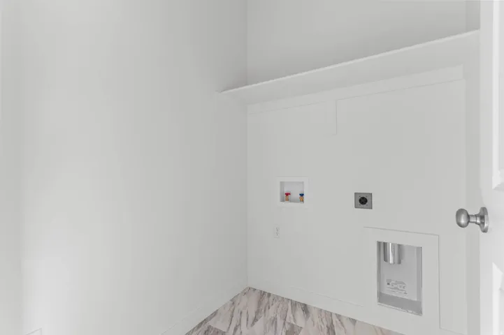 Laundry area featuring a utility hookup, overhead shelving, and wood-finish flooring
