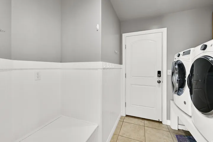 Integrated laundry area with tile flooring and a built-in bench