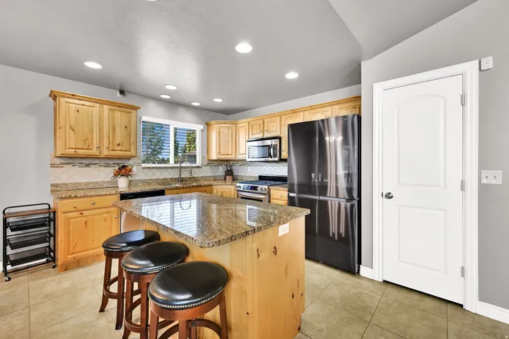 Kitchen featuring wood cabinetry, a center island with countertop seating, stainless steel appliances, a tile backsplash, and recessed lighting