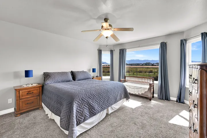 Carpeted flooring, ceiling fan, multiple windows with expansive outdoor scenery, and light gray wall paint