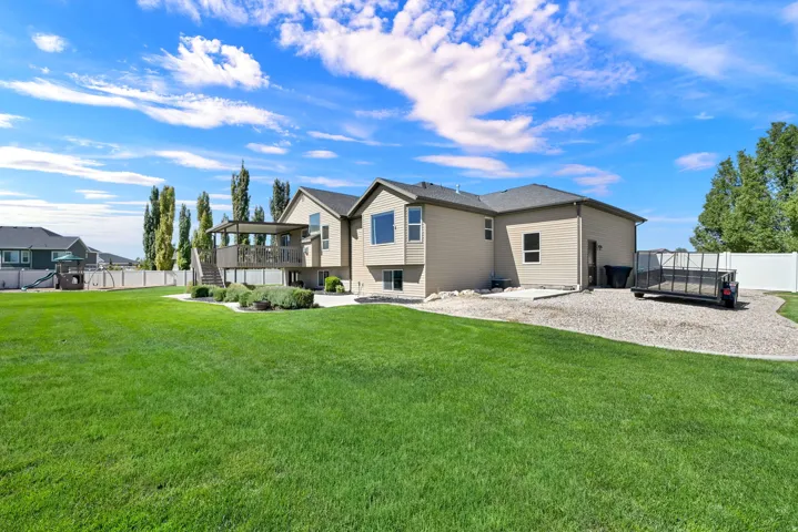 Expansive backyard featuring a manicured lawn, a gravel parking area, and a private fenced perimeter