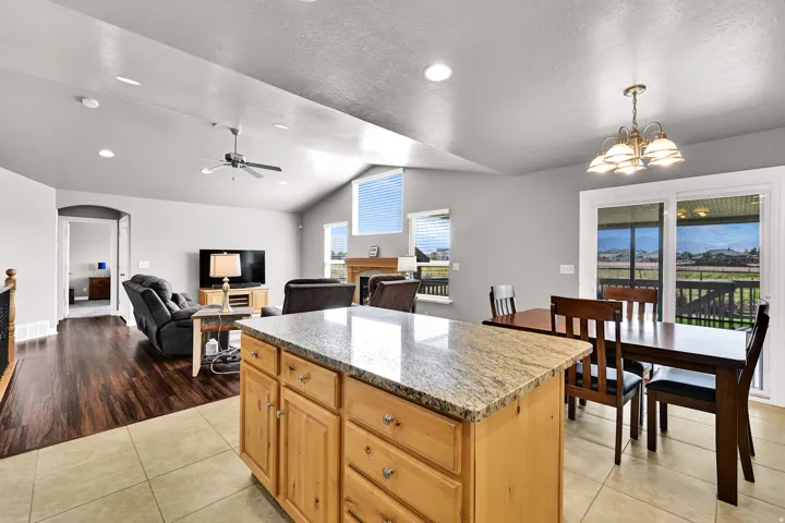 Kitchen island with stone countertop, tile flooring, wood-finish flooring, vaulted ceiling, and sliding glass door
