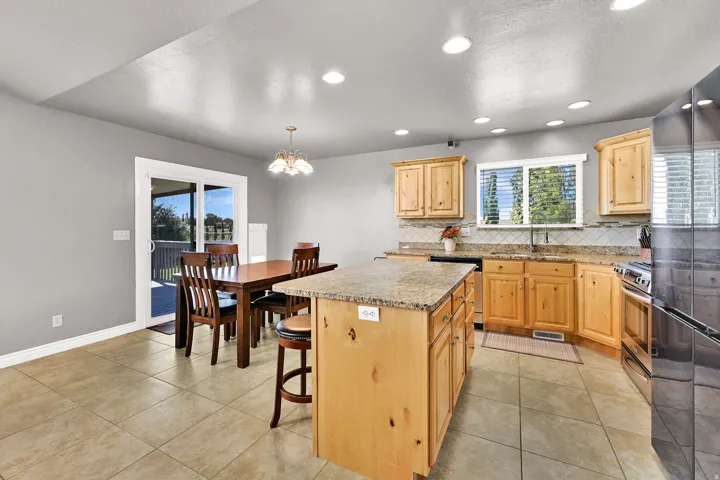 Kitchen featuring wood cabinetry, granite countertops, tile flooring, recessed lighting, and a sliding glass door to an outdoor deck