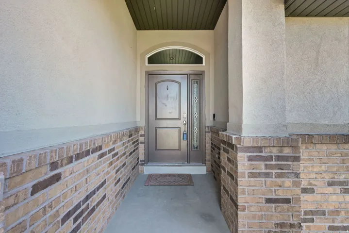 Entryway featuring a decorative front door with an arched transom, stucco exterior, and brick wainscoting