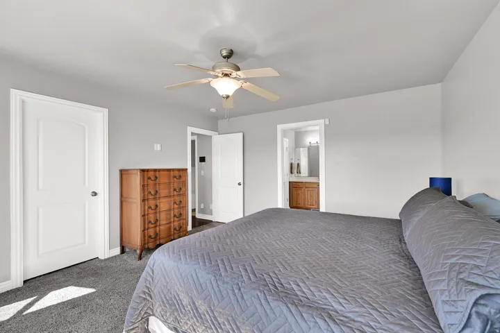 Ceiling fan with integrated lighting, neutral wall paint, white interior doors, and gray carpet flooring