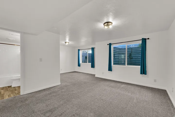 Plush carpet flooring, multiple windows, recessed lighting, and a full bathroom with a tiled shower surround and wood-finish flooring